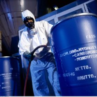 HAZWOPER certified man in hazmat suit with barrel of chemicals